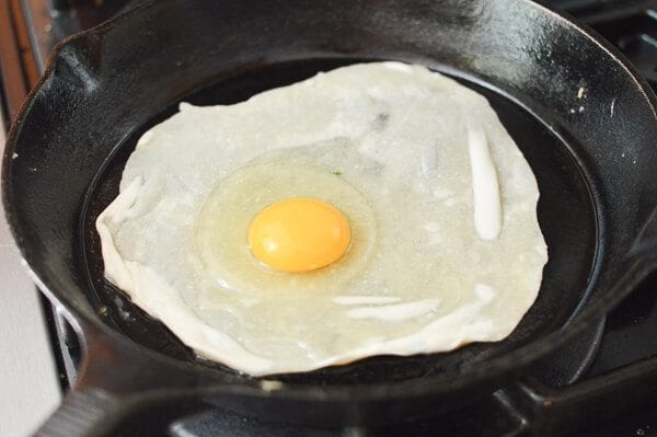 raw egg on thin dough in pan for Jidan Bing, by cwww5.fioekdjsdas.cf