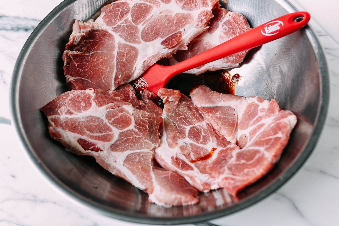 Adding pork pieces to marinade