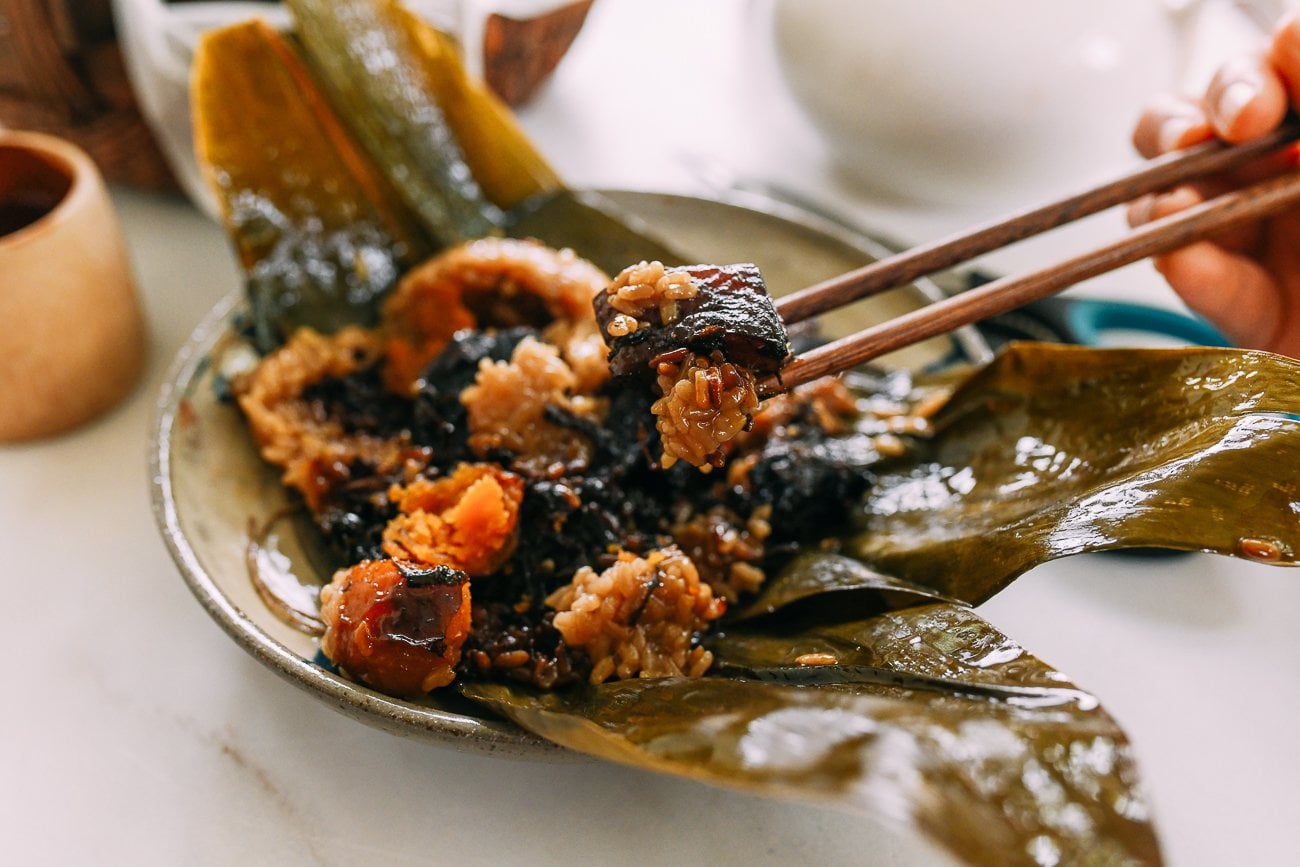 Digging into a sticky rice parcel (zongzi) with pork belly, salted egg yolk, and preserved vegetable