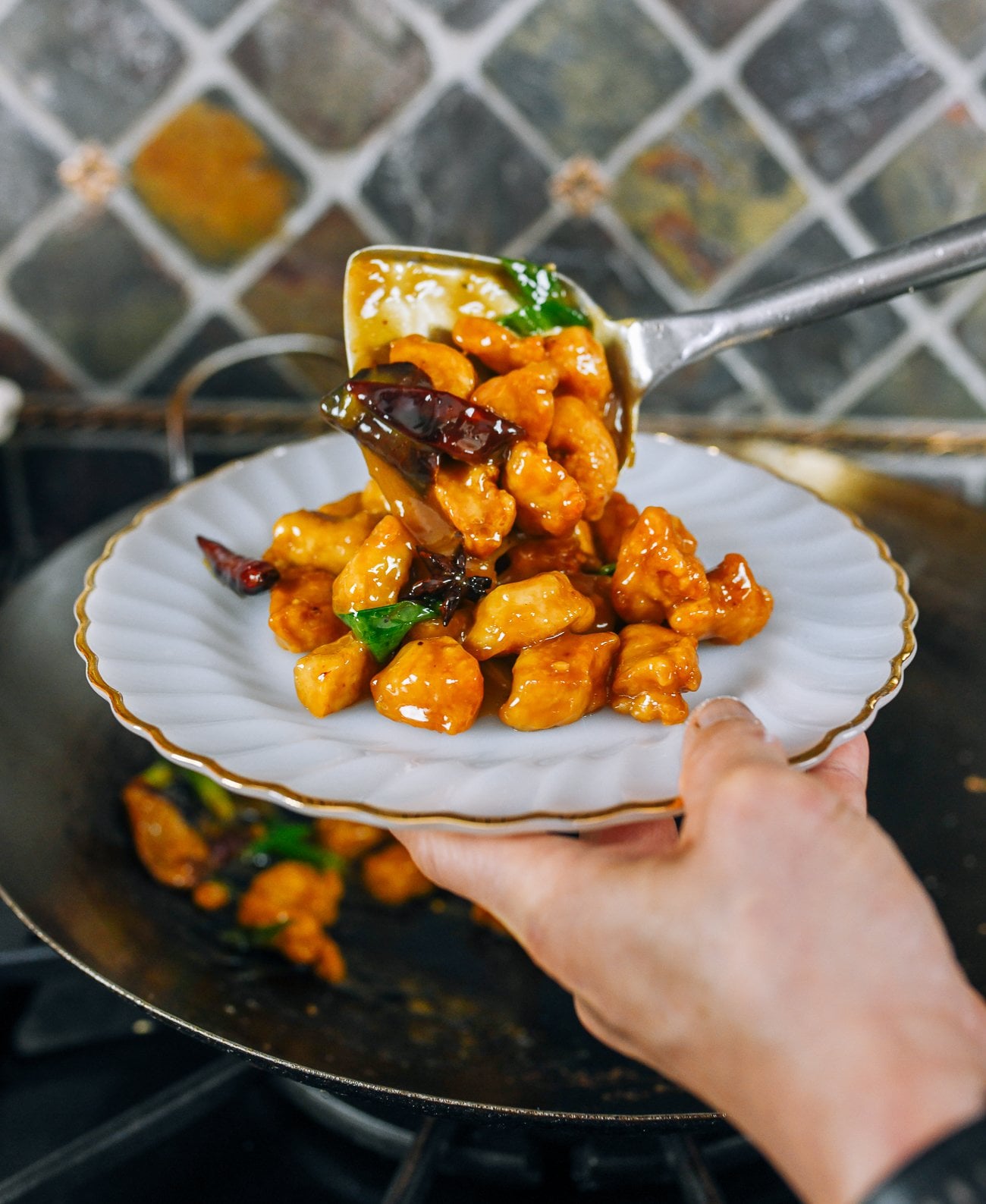Transferring orange chicken from wok onto serving plate