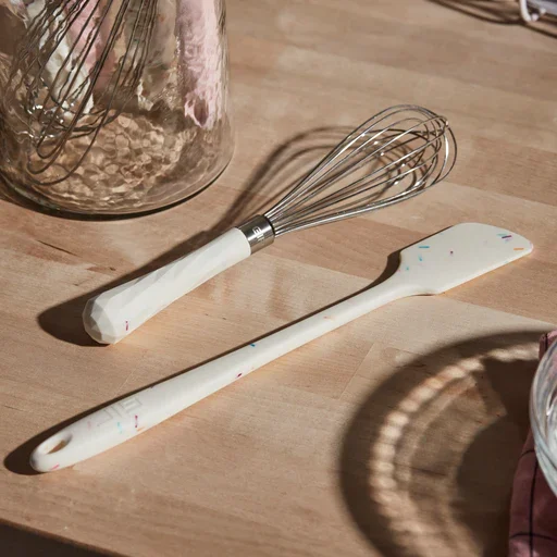 mini whisk next to a mini rubber spatula in confetti white patterned handles
