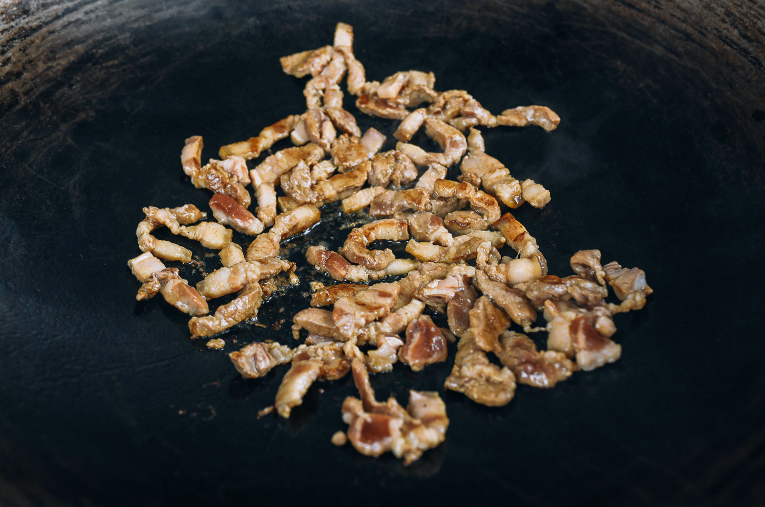 seared strips of pork belly in wok