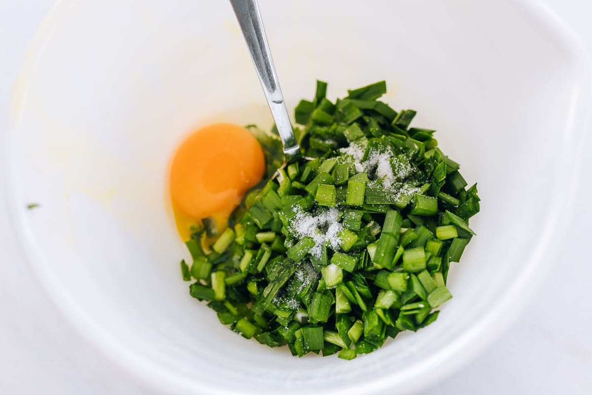 chopped garlic chives, egg, and salt in bowl