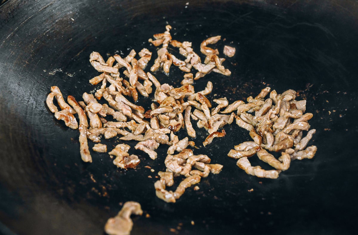 seared pork strips in wok