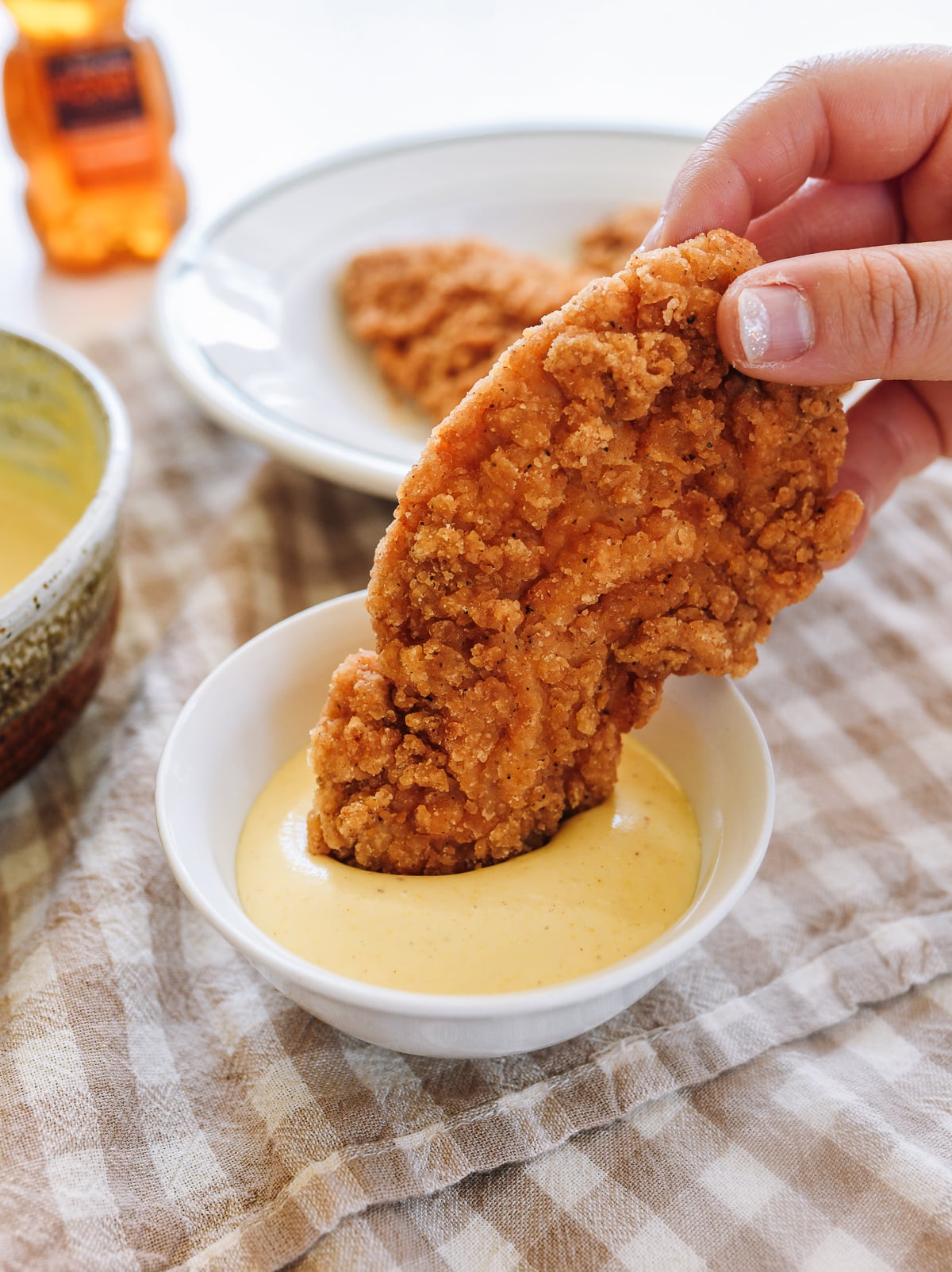 dipping chicken tender into honey mustard sauce