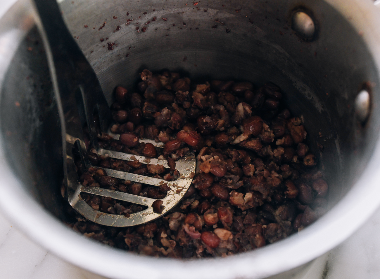 mashing red beans in pot